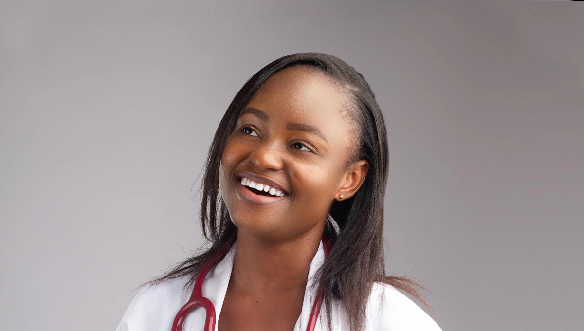 A smiling doctor in a white coat, a stethoscope around her neck.